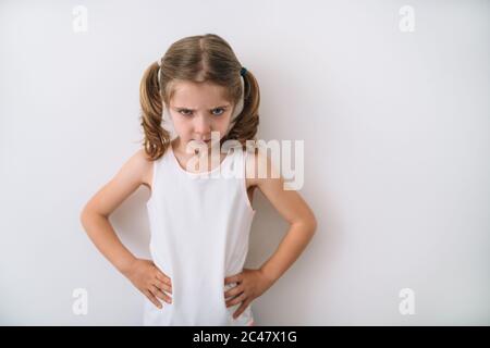 portrait of a beautiful blonde girl with blue-eyed pigtails showing an angry face on a white background Stock Photo