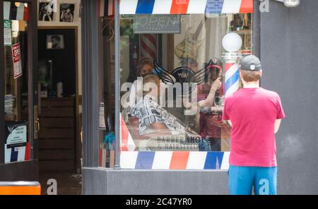 Toronto, Canada. 24th June, 2020. A hairdresser wearing a face mask cuts a man's hair at a hair salon in Toronto, Canada, on June 24, 2020. The City of Toronto moved to the next stage of the economic reopening on Wednesday amid the COVID-19 pandemic, with restrictions lifted for restaurant patios, hair salons, and malls. Credit: Zou Zheng/Xinhua/Alamy Live News Stock Photo