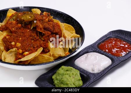 mexican nachos chips with chili beef, avocado, sour cream and tomato salsa Stock Photo