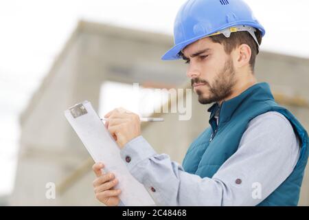 portrait of serious builder man writting on clipboard Stock Photo