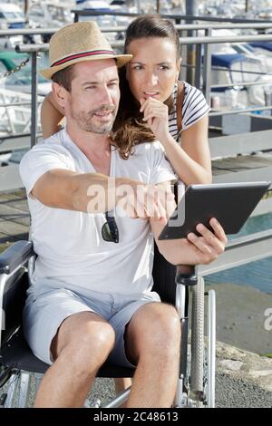 woman and his boyfriend on the wheelchair checking something oudtoors Stock Photo