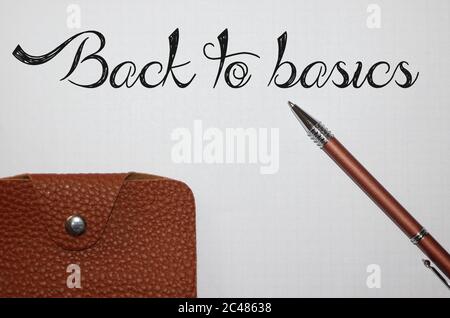 Pen writing the word Back To Basics on white paper and brown leather wallet. Financial education concept Stock Photo