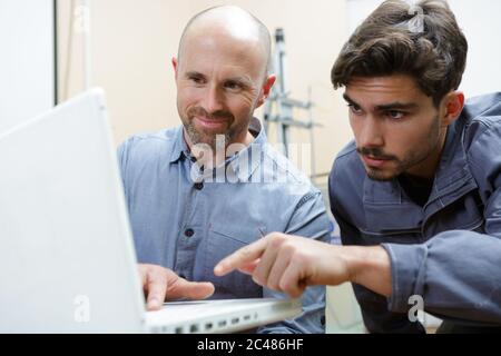 engineer showing apprentice how to measure cad drawings Stock Photo