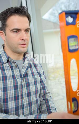 man checking upright surface with spirit level Stock Photo