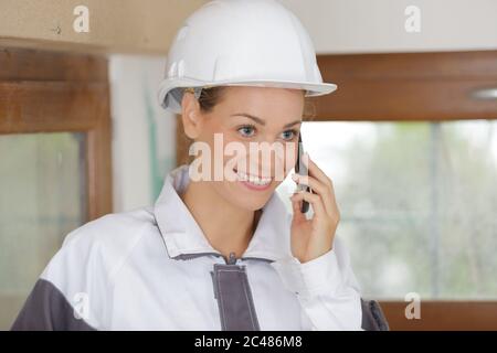 smiling female contruction worker using cellphone Stock Photo