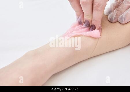 liquid wax for pink depilation drains from the stick. The concept of  depilation, waxing, smooth skin without hair. Stock Photo