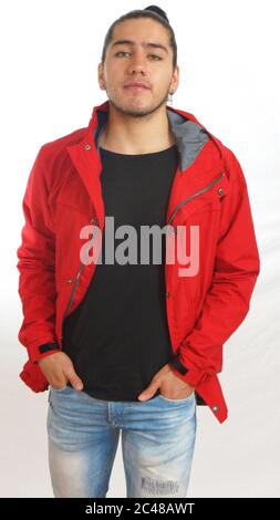 Young hispanic man with gathered hair done bow wearing black t-shirt and red jacket, hands in pockets of pants, posing facing the camera on white back Stock Photo