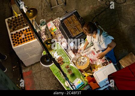 SAMUT PRAKAN, THAILAND, OCT 24 2019, Woman sell grilled meat on stick in stall on street at Phra Samut Chedi Temple Fair. Thai food at the night marke Stock Photo