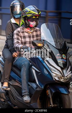 Couple on motorcycle, wearing face mask, during Covid 19 pandemic, Bangkok, Thailand Stock Photo