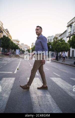 Successful young businessman walking in the street during daytime Stock Photo