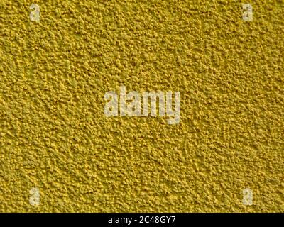 yellow ocher stucco texture on exterior wall with fine grains. sandpaper like sandy gritty rough surface. closeup view. patterns and textures concept Stock Photo