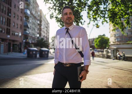 Successful young businessman walking in the street during daytime Stock Photo