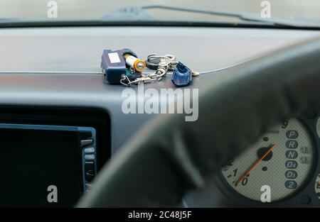 the disassembled alarm key is on the car dashboard and an old battery for replacement Stock Photo