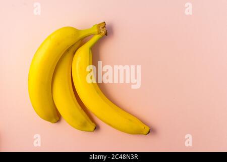 yellow bunch of ripe bananas on a pink paper background, copyspace, horizontal position Stock Photo