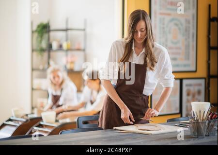 Women working In pottery studio, smiling and talking. Ceramic workshop, pottery master class. Stock Photo