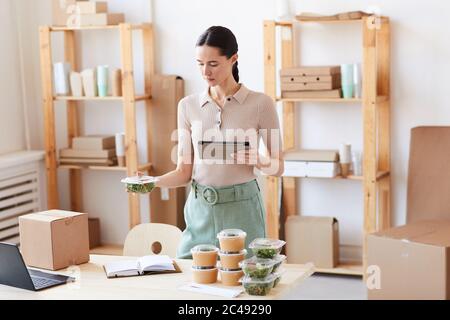 Young woman using digital tablet she working at office and organizing the food delivery Stock Photo