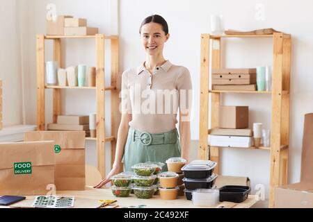 Portrait of young woman smiling at camera while standing at office she working at food delivery service Stock Photo