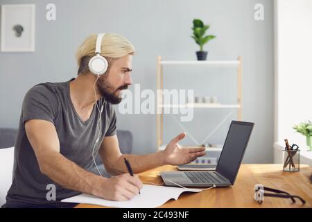 Working from home or online education. Attractive businessman in headset having web conference on laptop at workplace Stock Photo