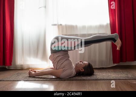 yoga girl in pose halasana or Plow pose at home. Stock Photo