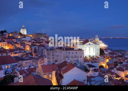Twilight view over Alfama (ancient quarter of Lisbon, Portugal) as seen from the Miradouro (Belvedere) de Santa Lucia with St-Stephen Church