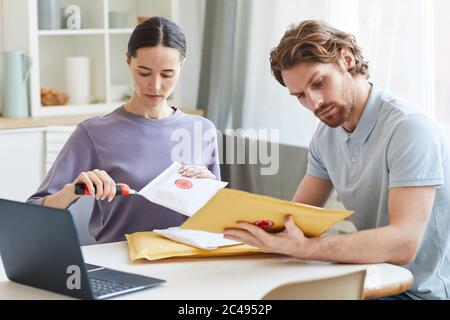 Young couple sitting at the table and opening the parcels together at home Stock Photo