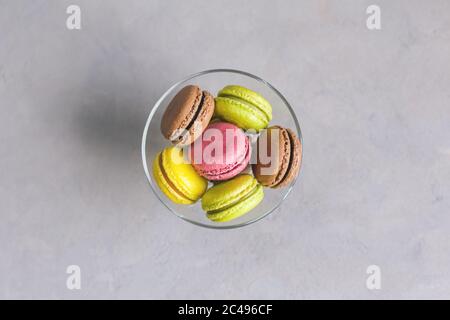 Tasty multi-colored french macaroons on a grey background. Pink, green and brown macaroons. Place for text. Stock Photo