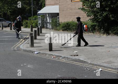 Volunteers clean up in Overton Road, Angell Town, Brixton, south London, where riots and violent confrontations with police took place overnight. Fifteen officers were injured and four people were arrested following the incident. Stock Photo