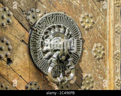 Carved brass door handle shaped as lion on old wooden door in Tallinn, Estonia Stock Photo