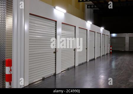 Row of white doors indoor storage units in a self storage facility. Rental Storage Units with red white safety pole. Netherlands Stock Photo
