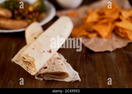 Twisted in a pita bread roll lie on a wooden table. Close-up Stock Photo