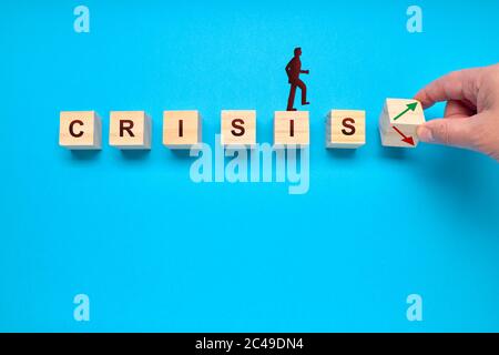 Hand is turning a dice and changes the direction of an arrow, symbolizing that the crisis is changing. Economy concept Stock Photo