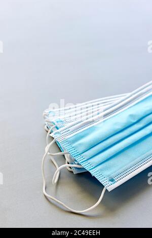 Coronavirus protection. Blue antiviral medical face masks. Surgical protective masks with ear loops on grey background. Vertical image with copy space Stock Photo