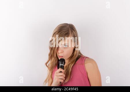 Young cute girl holding a microphone singing karaoke Stock Photo