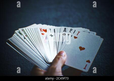 Human hand holding a fan of playing cards on a dark blue background. Stock Photo
