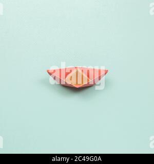 Pink paper ship on blue background. top view Stock Photo