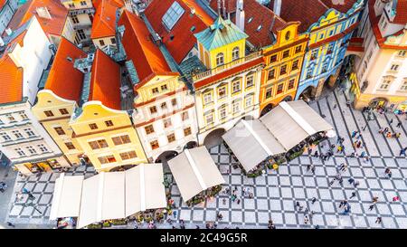PRAGUE - SEPTEMBER 26, 2019: Aerial view of historical houses at Old Town Square with restaurant garden tents and many tourists. Colorful residential buildings with red rooftops. Prague, Czech Republic. Stock Photo