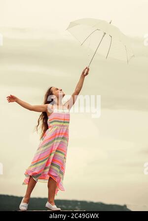 Feeling light. Anti gravitation. Fly drop parachute. Dreaming about first flight. Kid pretending fly. I believe i can fly. Touch sky. Girl with light umbrella. Fairy tale character. Happy childhood. Stock Photo