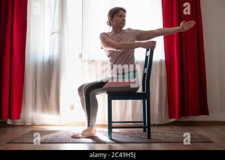 Woman working out doing yoga or pilates exercise using chair. Stock Photo