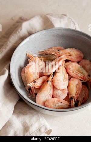 Frozen shrimps on gray plate close-up.Natural seafood ingredient for cooking.Vertical orientation Stock Photo