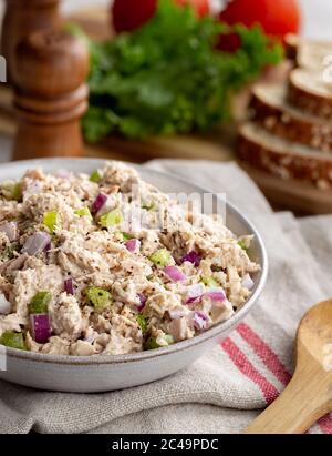 Tuna salad in a bowl on a napkin with makings for sandwiches in background Stock Photo