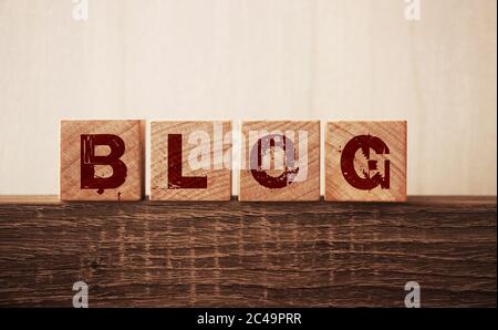 BLOG word written on wooden blocks on the edge of wooden table. Personal brand blogger concept, blogging as a profession, freelance online business Stock Photo