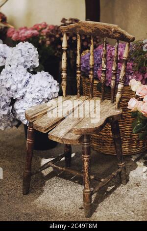 Vertical closeup shot of a vintage wooden chair surrounded by baskets with flowers