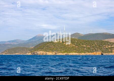 Hilly greek coast of the Gulf of Corinth in sunny day. Old lighthouse building and many wind farms Stock Photo