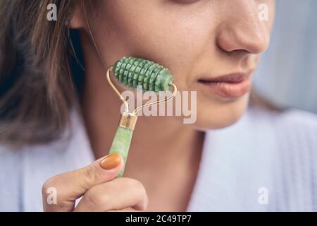 Young woman with perfect skin using face massager Stock Photo