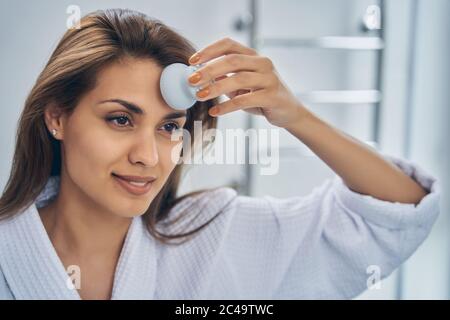 Charming young woman using facial massage brush Stock Photo