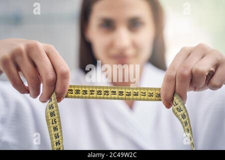Charming young woman holding yellow tape measure Stock Photo