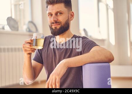 Bearded young man drinking herbal tea in yoga studio Stock Photo