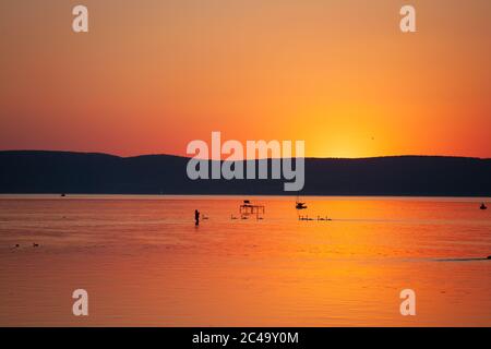 Sunset over lake Balaton in vivid orange color with silhouettes Stock Photo