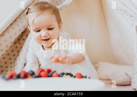 Baby girl dressed up in bright clothing celebrates her one year birthday at home Stock Photo