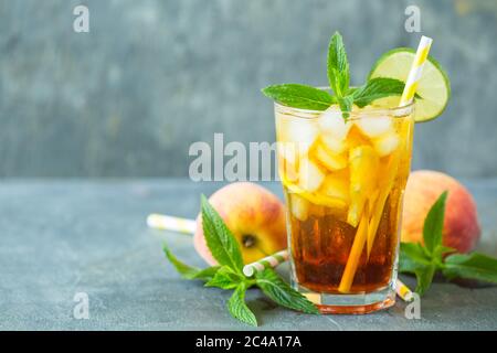 Homemade peach ice tea with ice, lime and mint in the glass Stock Photo